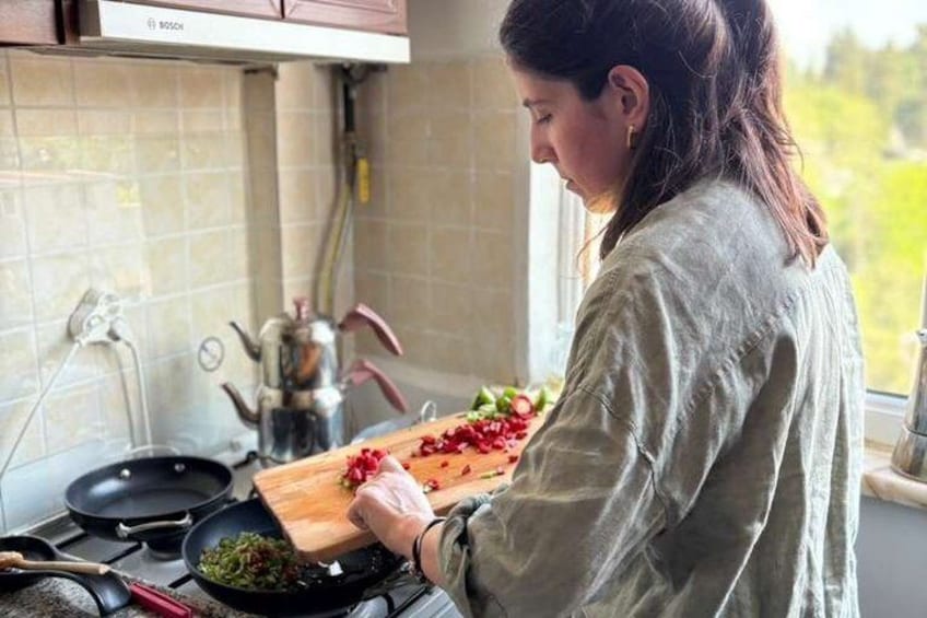 A person chopping vegetables on a wooden cutting board in a kitchen with a stove and a kettle. 5