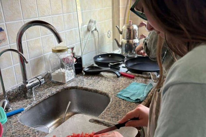 A kitchen with a sink, a faucet, a cutting board, and a person chopping vegetables. 4