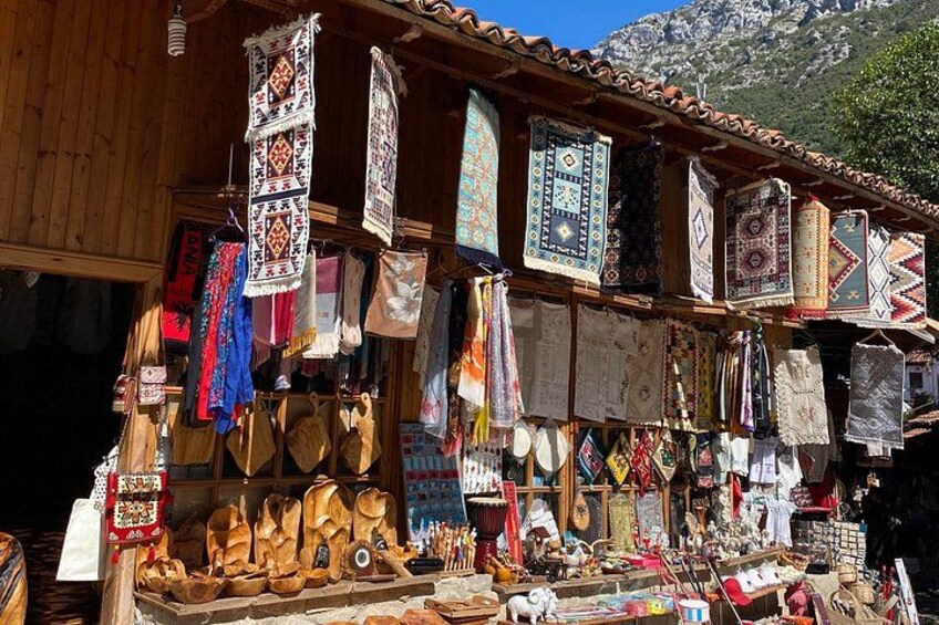 A wooden building with various textiles and wooden items displayed outside. 5