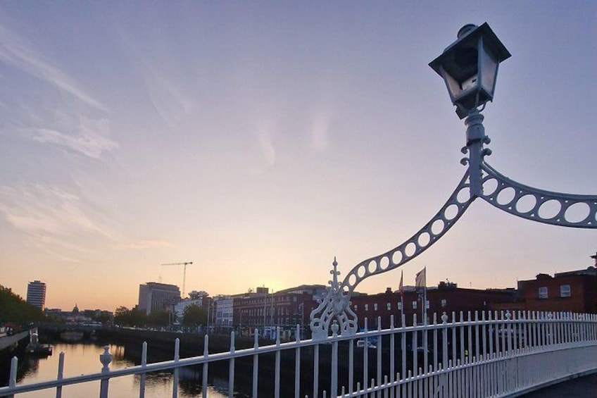 A bridge with a decorative lamp post, a river, and buildings in the background. 2