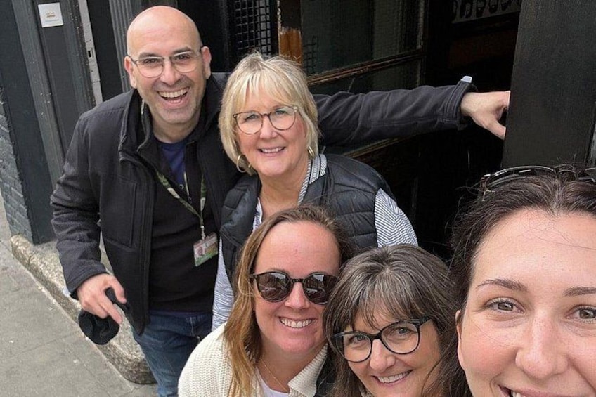 A group of people standing outside a building with a black door. 5