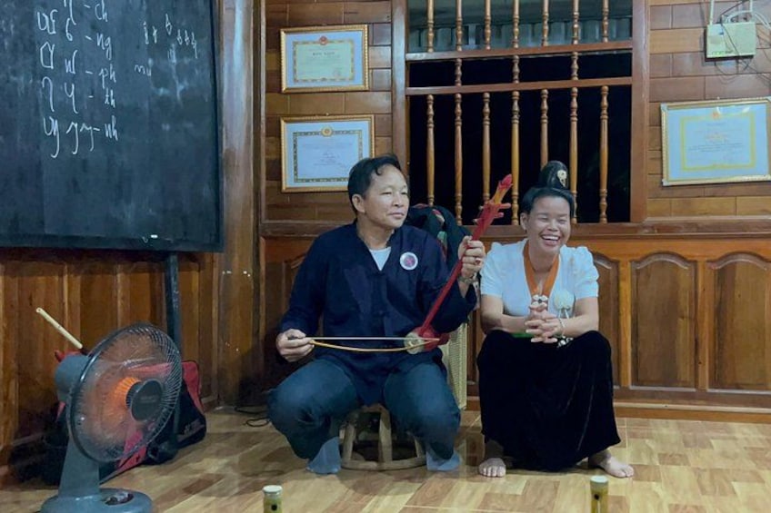 Two people sitting on chairs, a fan, and a blackboard with writing. 5
