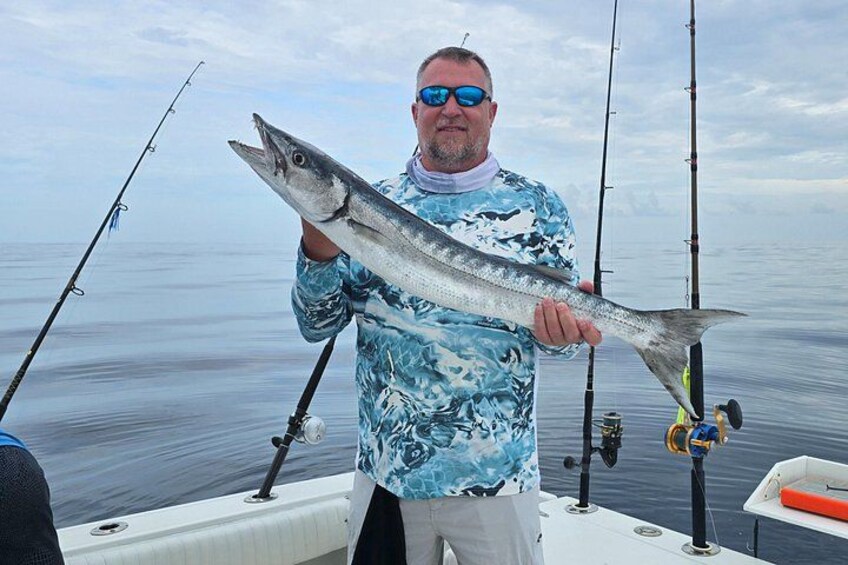 A person holding a large fish on a boat with fishing rods. 3