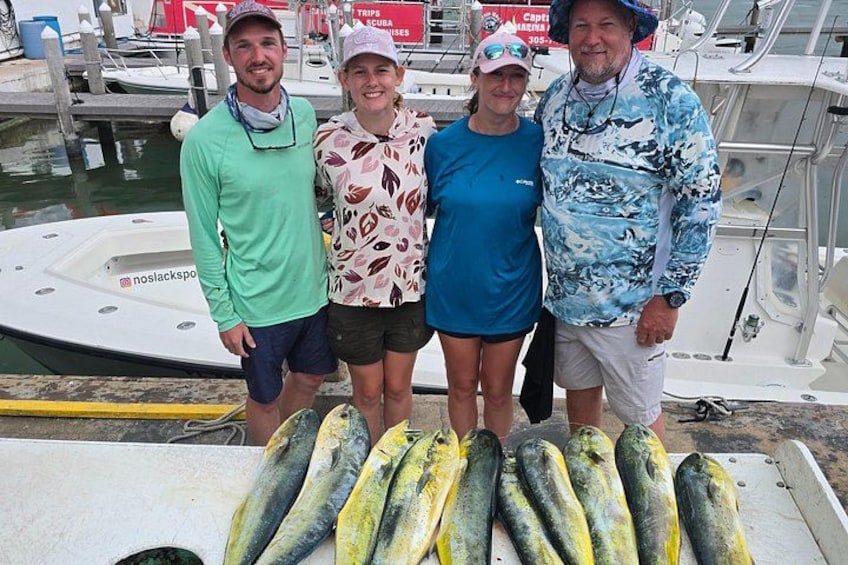 Four people standing on a boat with a row of fish in front of them. 4