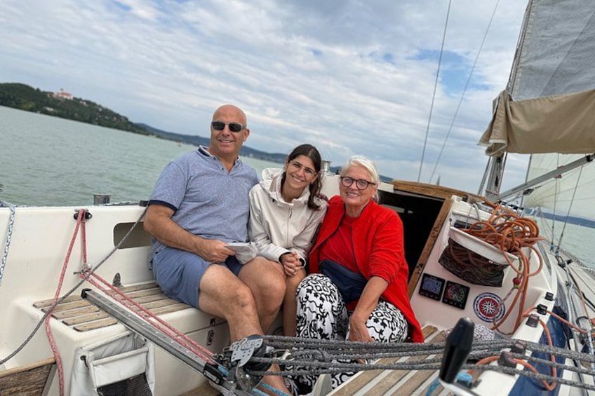 Three people on a sailboat with a lake and a distant island in the background. 5