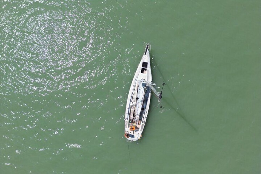 A white boat with a cabin and a small deck, anchored in calm greenish water. 5