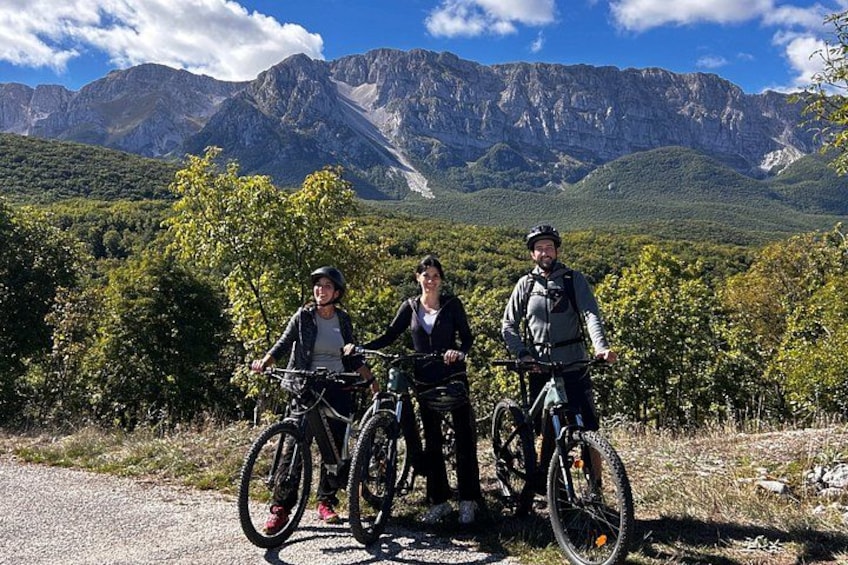 Three people on bicycles in a mountainous area with greenery and rocky terrain. 4