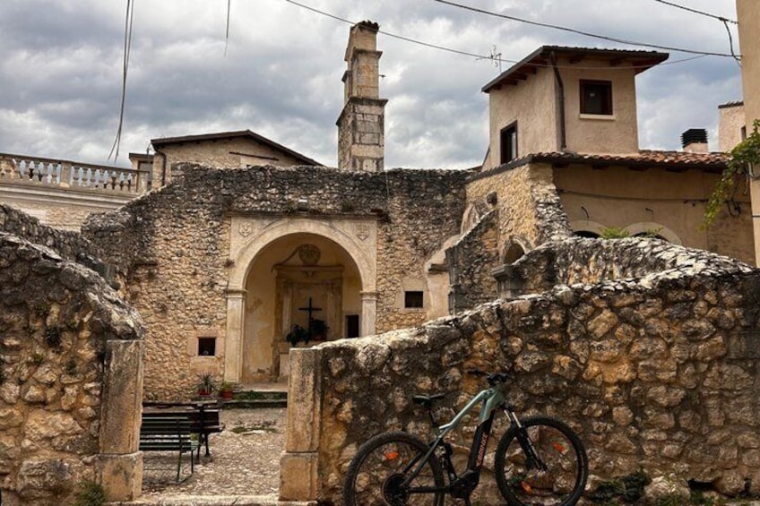 A stone archway leading to a building, a bicycle leaning against a wall, and a bench in the foreground. 5