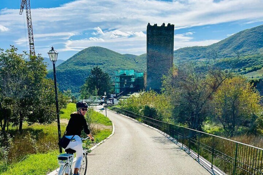 A cyclist on a road with a castle and a tower in the background. 1