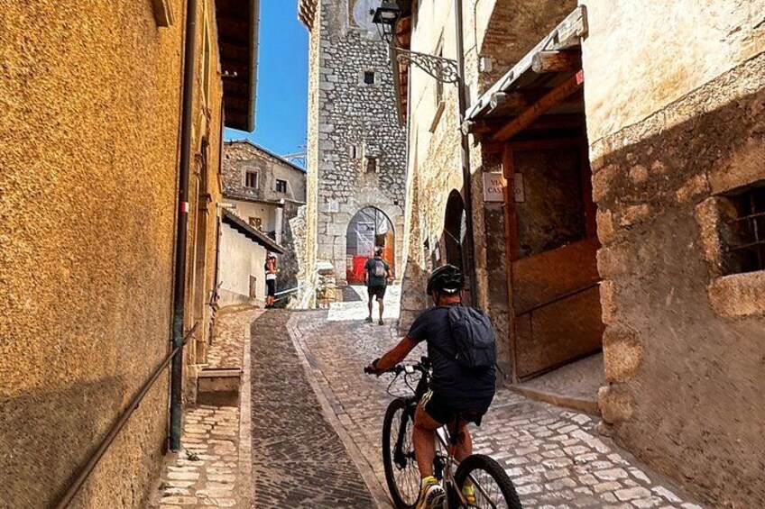 A narrow cobblestone street with a cyclist and a pedestrian in the distance. 2