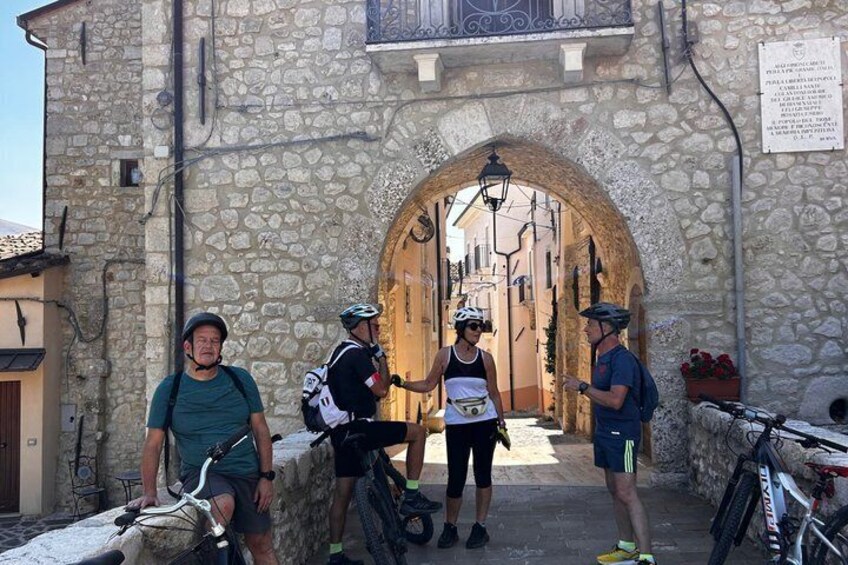 A stone building with an arched entrance, a bicycle, and a person wearing a helmet. 3