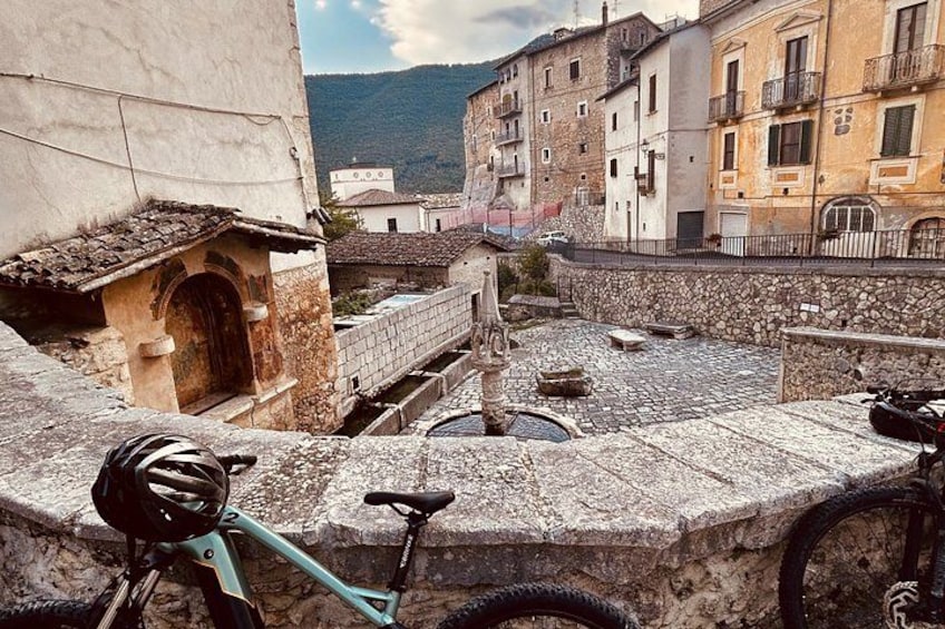 A stone staircase leading to a building, a bicycle parked on the steps, and a view of a hillside in the background. 2