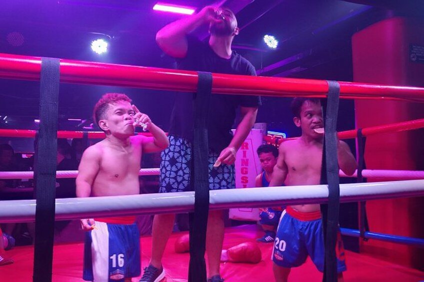 Ein Boxring mit zwei Personen darin, eine trägt die Nummer 16 auf der Shorts und die andere die Nummer 20. 3