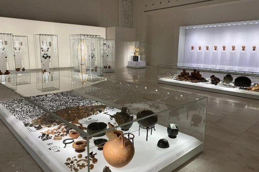 Et indendørs museum med glasmontre, der indeholder keramik og artefakter. 3