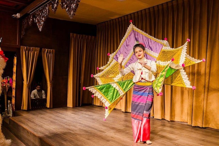 A person performing with a colorful kite in a stage setting. 1