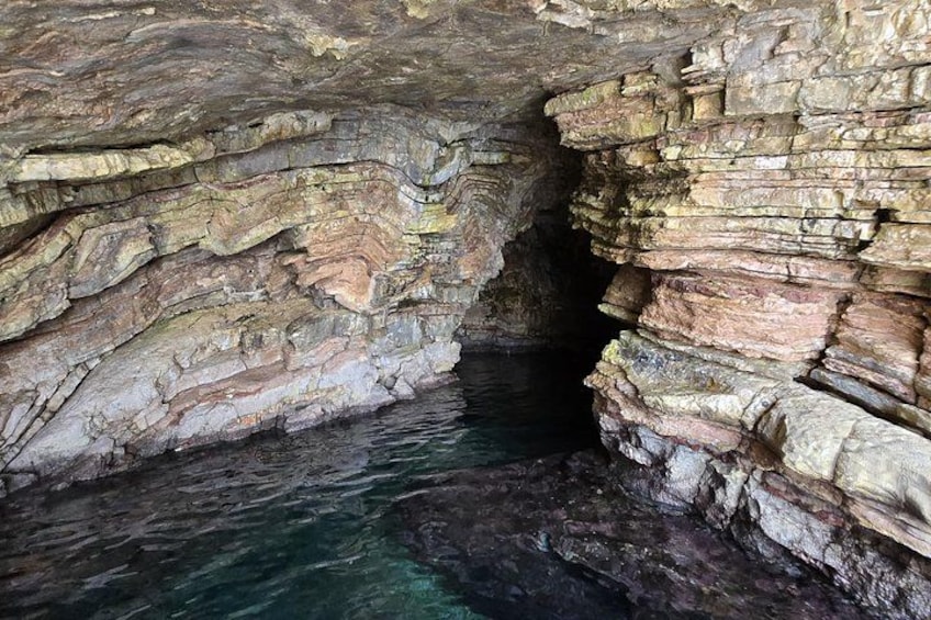 A natural rock formation with layered strata and a water body. 2