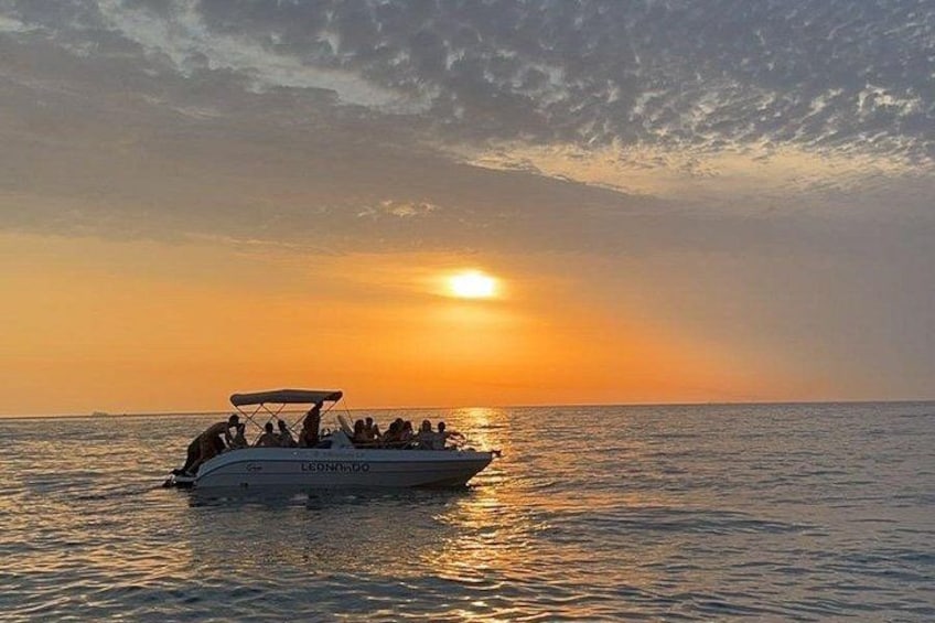 A boat with people on a calm sea during sunset. 1