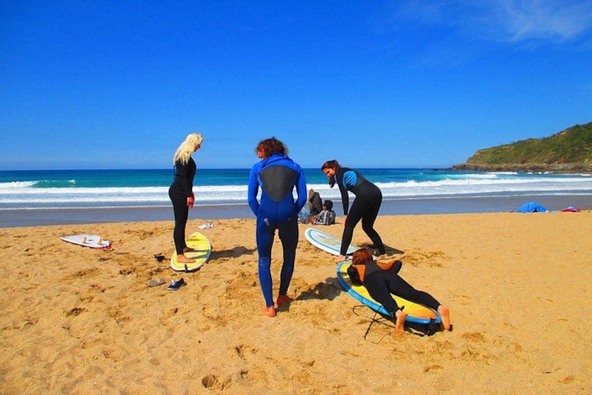 A beach with people in wetsuits preparing surfboards. 3