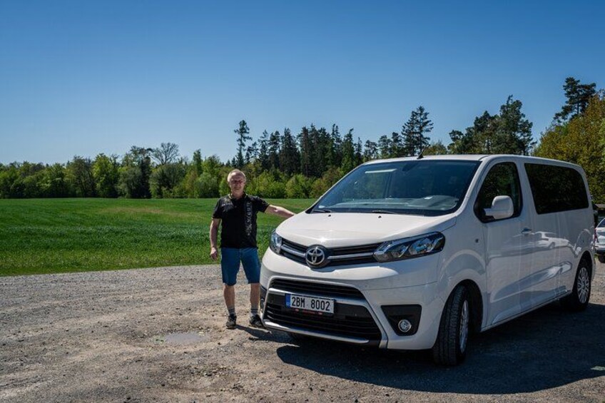 A white van parked on a gravel surface with a person standing beside it. 2