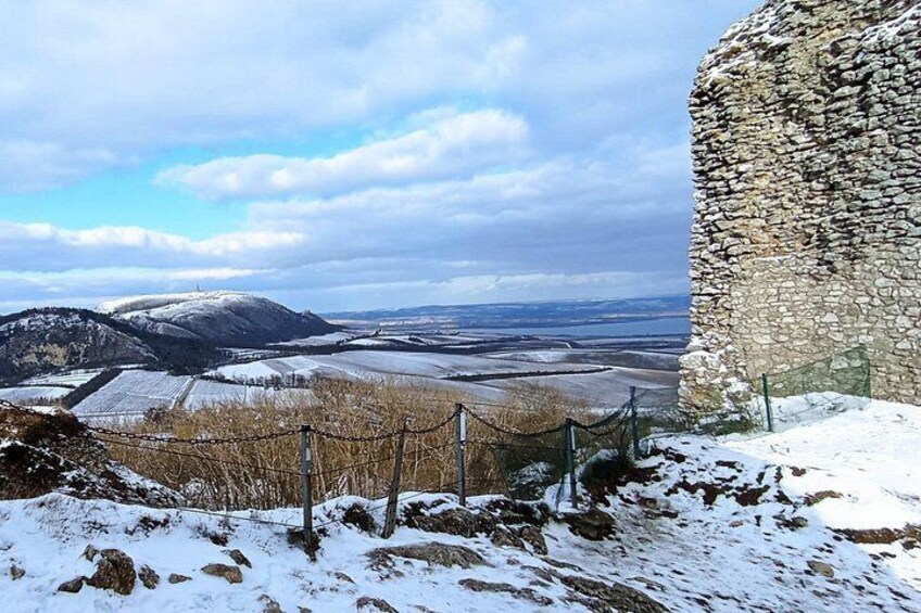 A stone wall, a fenced area, and a snowy landscape with distant fields. 4