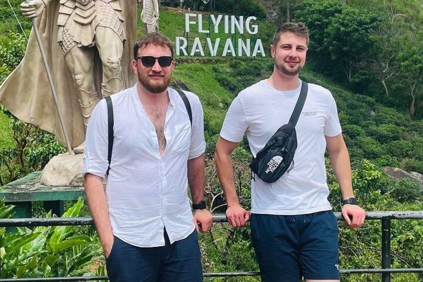 Two people standing in front of a statue with the text 'FLYING RAVANA' visible. 2