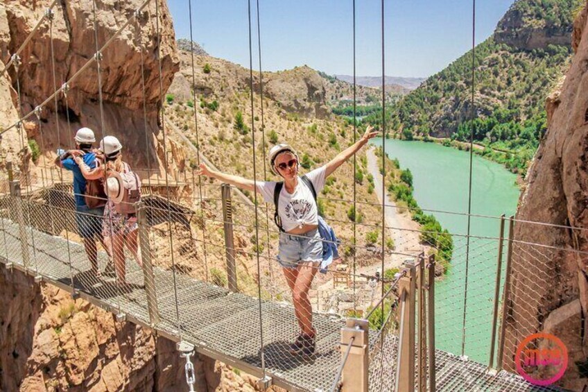 A person on a suspension bridge with a river and mountains in the background. 5