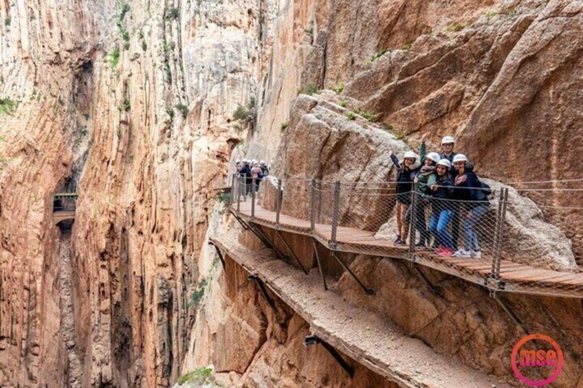 A group of people on a wooden bridge in a canyon. 4