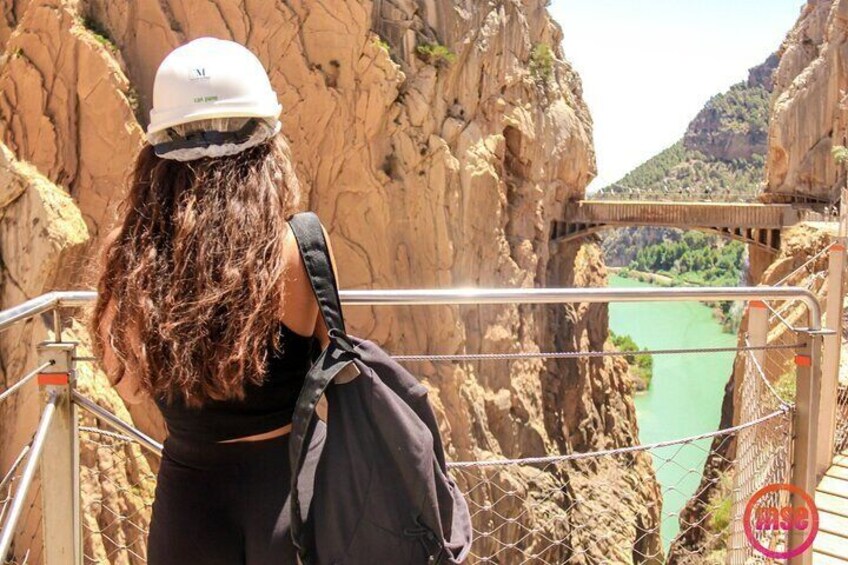 A person standing on a bridge railing overlooking a river. 1