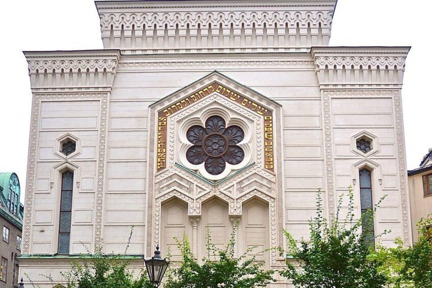 Un edificio con detalles arquitectónicos ornamentales, incluyendo un gran motivo floral central y ventanas simétricas. 1