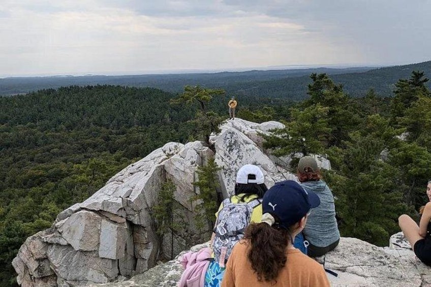 A group of people on a rocky outcrop overlooking a forested valley. 2