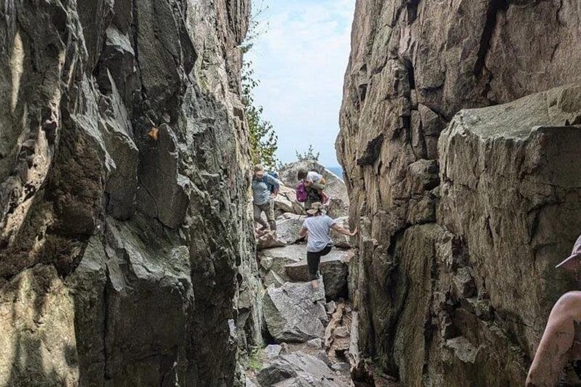 A narrow canyon with rocky terrain and hikers climbing. 2