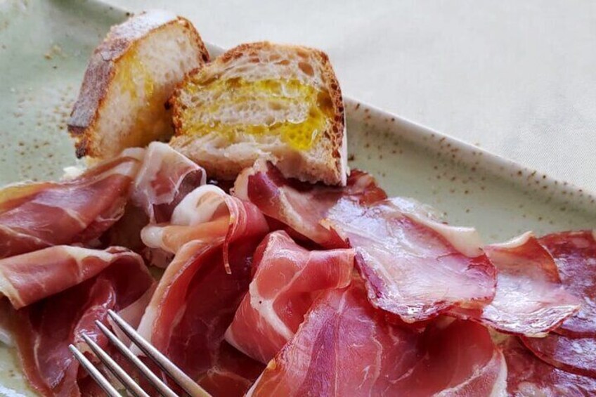 A plate of sliced cured meat and toasted bread. 2