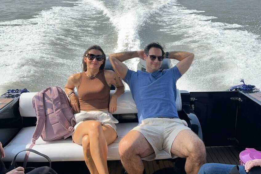 Two people on a boat with a wake behind them. 1