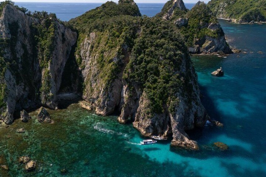 A boat navigating a narrow passage between rocky cliffs with clear turquoise waters. 5