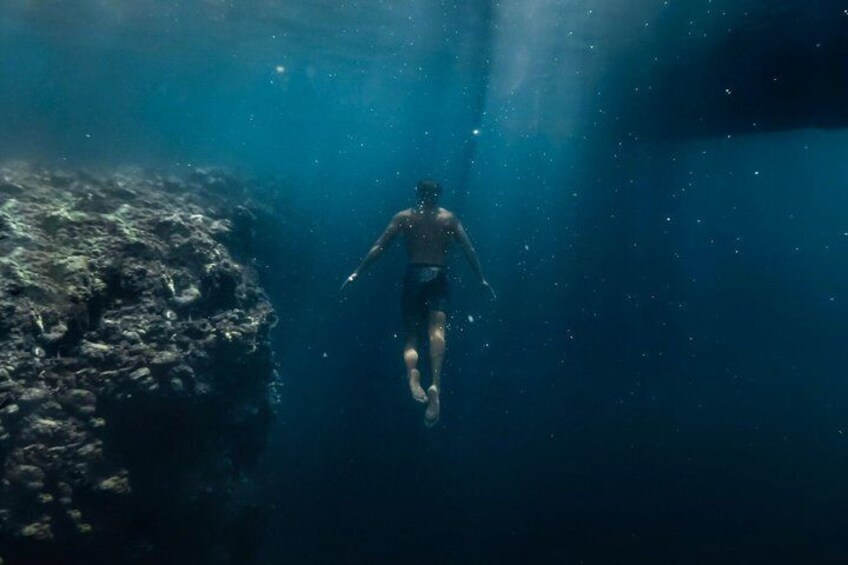 A person swimming underwater near a rocky formation. 2