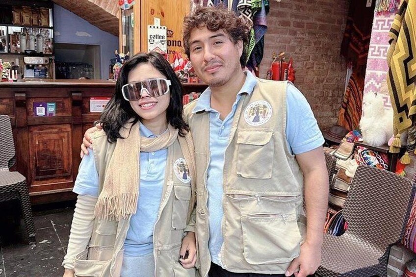 Two people standing in a cafe with a brick wall and various items on display. 2