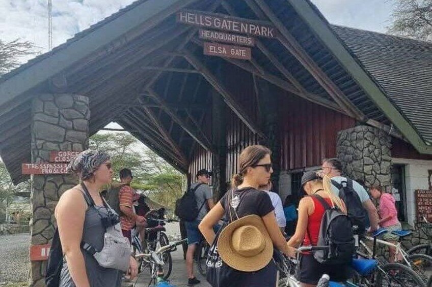 A group of people at Hells Gate Park, with signs indicating the entrance and a nearby restroom. 1