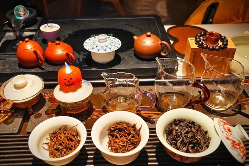 A table with various tea sets, including teapots, cups, and bowls, some with Halloween-themed designs. 4