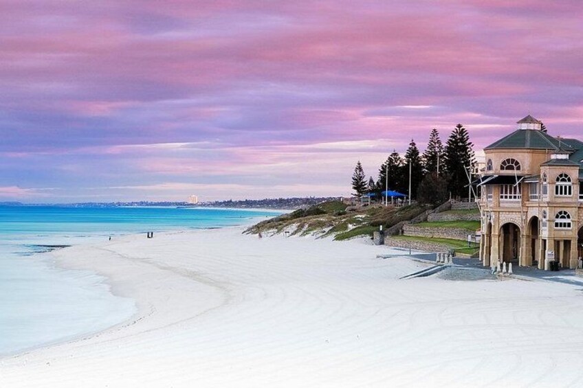 A beach with a large building, a clear sky, and a distant shoreline. 2