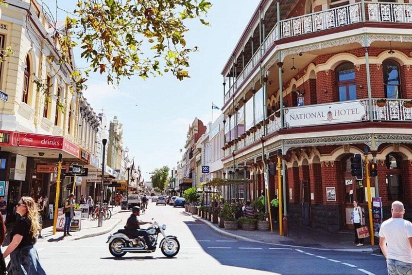 Una calle con una motocicleta, edificios y un cartel del Hotel Nacional. 5
