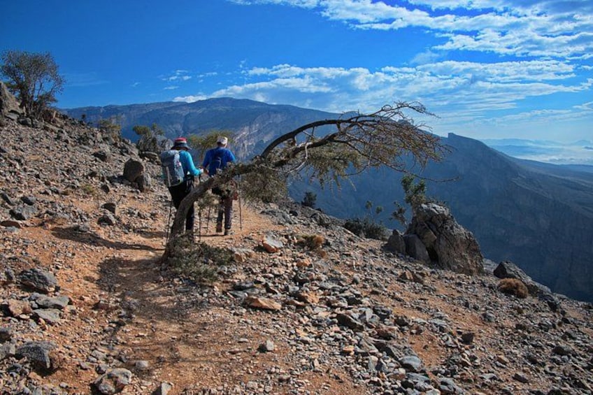 Two hikers on a rocky trail with a mountainous landscape in the background. 2