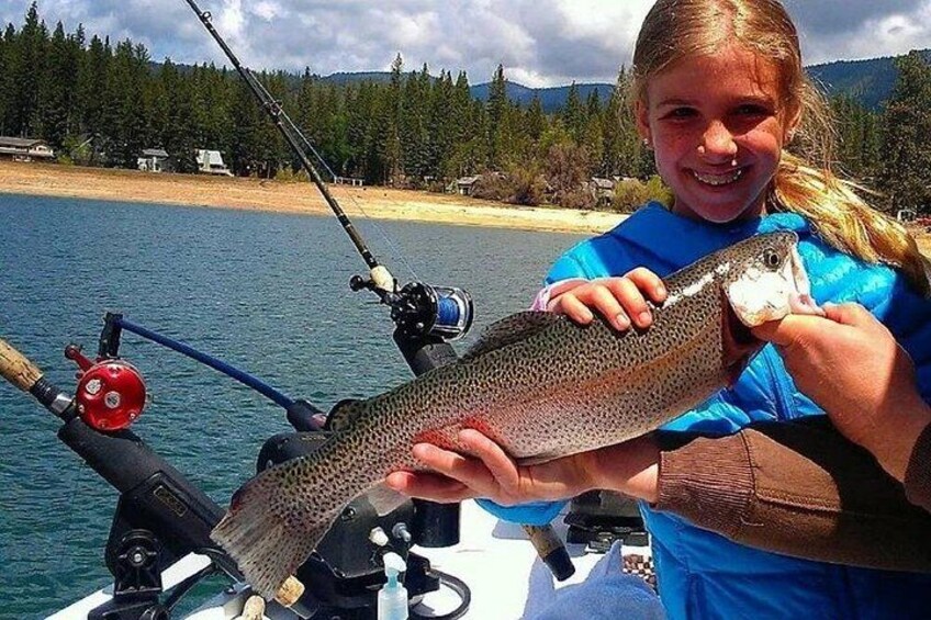 A person holding a fish near a boat with fishing rods. 2