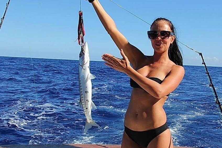 A person on a boat holding a fish. 4
