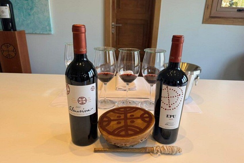 Two wine bottles, a pie, and glasses on a table. 1
