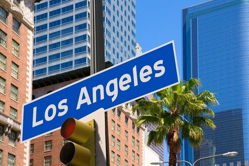 A street sign reading 'Los Angeles' with tall buildings and a palm tree in the background. 2