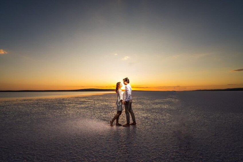 Two people walking on a beach at sunset. 5