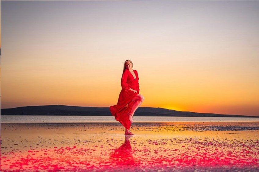 A person in a red dress standing on a beach with a sunset in the background. 2