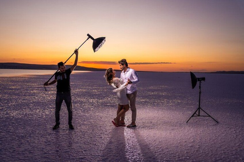 A couple on a beach at sunset with a photographer and lighting equipment. 3