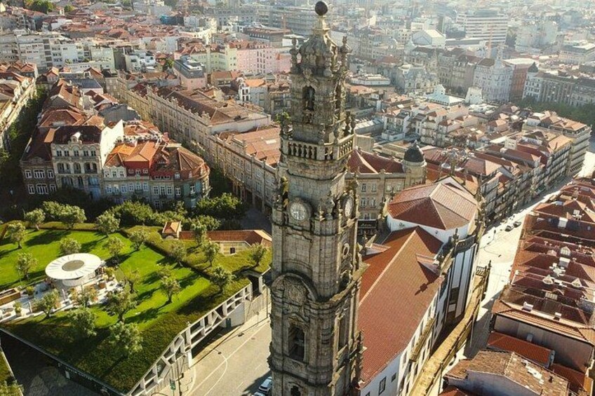 Ein historischer Turm mit einer Uhr, umgeben von einer Stadtlandschaft mit roten Dächern und einem grünen Park. 2