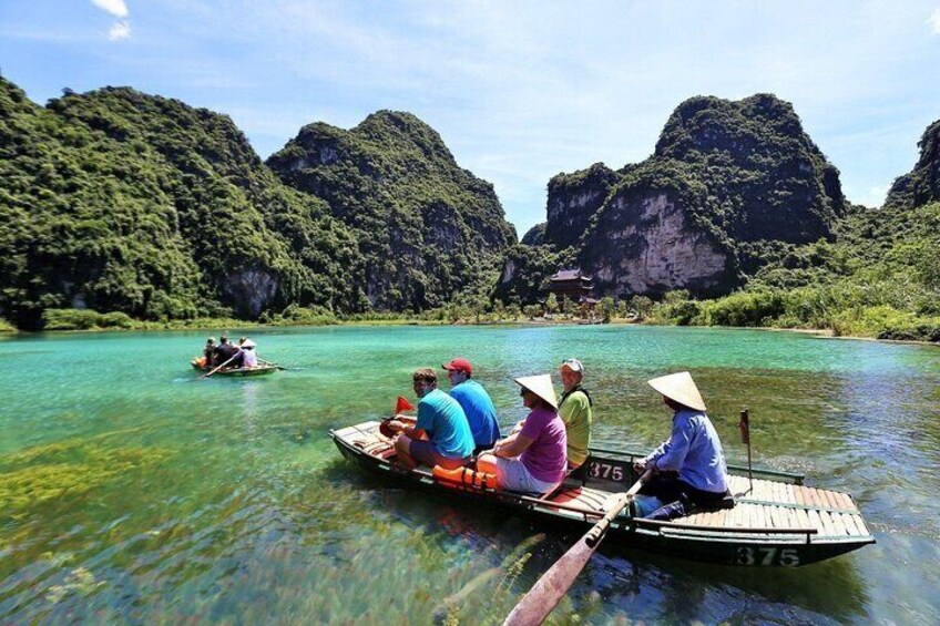 A group of people on a boat in a clear river surrounded by lush green mountains. 3